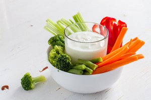 Vegetable sticks and yogurt dip, white wood background